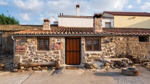 Un edificio de piedra con tejado de tejas, una puerta de madera y un letrero que dice 'La Cuadra'.