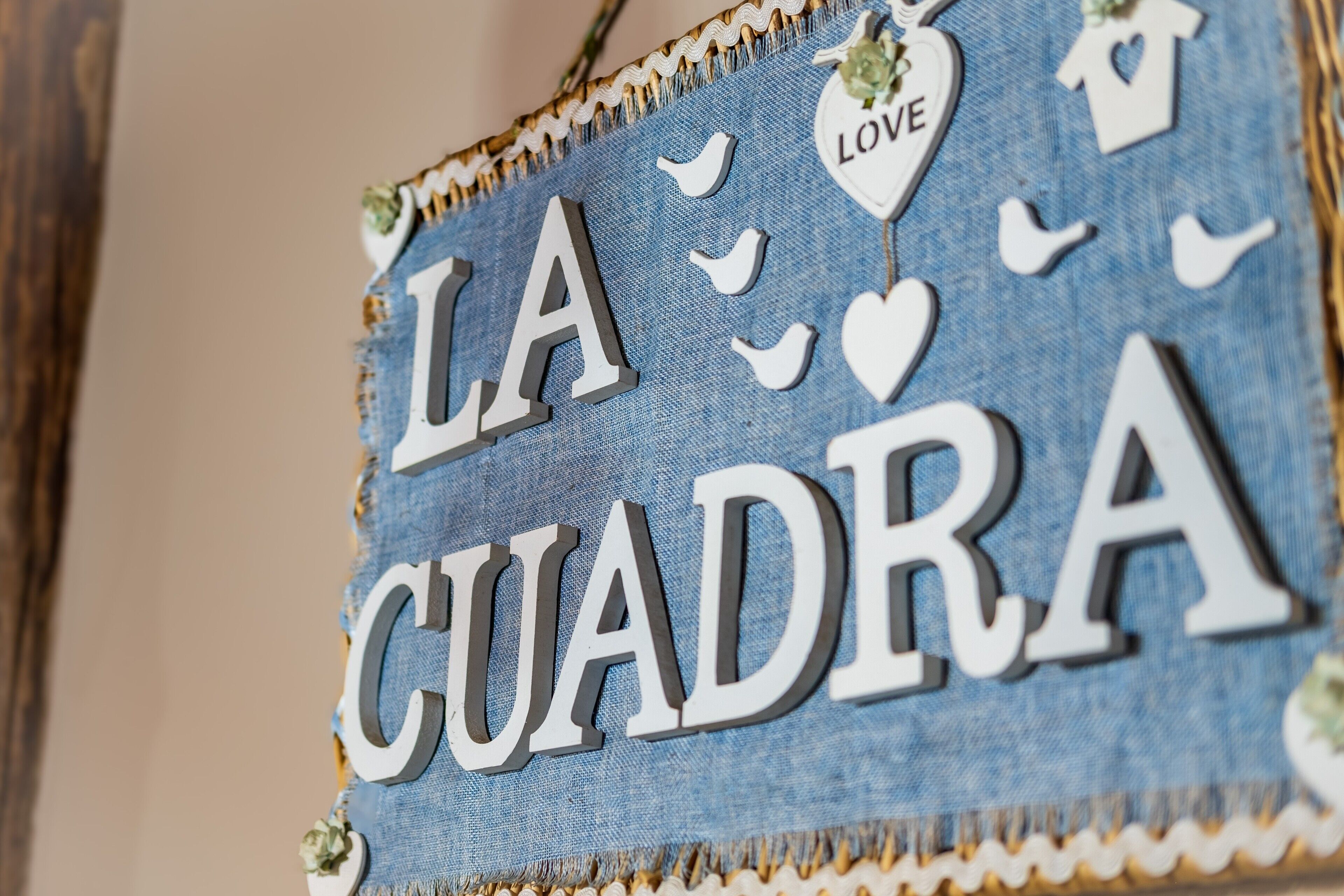 Segnaletica in denim con la scritta 'LA CUADRA' ed elementi decorativi.