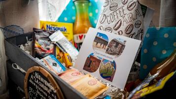 Laatikko, joka on täynnä kahviin liittyviä tuotteita, kuten Nespresso-kahvinkeitin, kahvipapuja ja kahviteemalla koristeltu kortti.