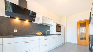 A modern kitchen with white cabinets, a black range hood, and a built-in oven. - Snjezana by Interhome (Crikvenica/Jadranovo)