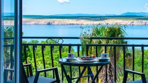 A balcony with a table set for two, overlooking a lake with distant mountains. - Snjezana by Interhome (Crikvenica/Jadranovo)