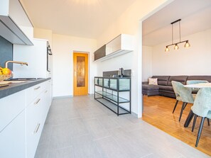 Une cuisine moderne avec des carreaux gris, une porte en bois et un coin repas comprenant un canapé gris et des chaises à rayures.