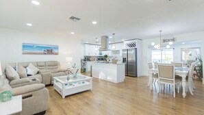 A spacious living area with a sofa, coffee table, and a dining area with chairs and a table. - MADEIRA BEACH RETREAT WITH HEATED POOL. (Seminole)