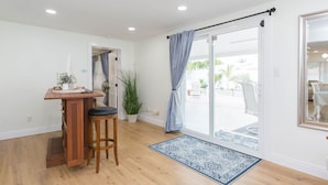 A room with a wooden bar area, a large sliding glass door leading to an outdoor patio, and a potted plant. - MADEIRA BEACH RETREAT WITH HEATED POOL. (Seminole)