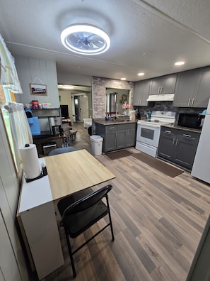 A modern kitchen with grey cabinets, a wooden dining table, and a ceiling fan. - Waterfront on Chassohwitzka river, 2/2, boat slip, floating dock, covered porch. (Homosassa)
