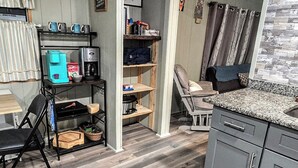A compact kitchen with wooden flooring, a coffee machine, and a seating area with a cushioned chair. - Waterfront on Chassohwitzka river, 2/2, boat slip, floating dock, covered porch. (Homosassa)