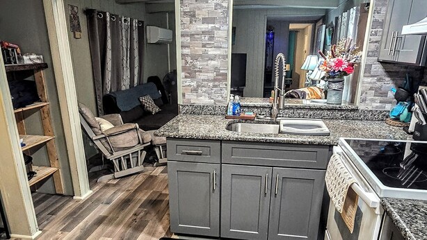 A compact kitchen with grey cabinets, a black countertop, and a stainless steel stove. - Waterfront on Chassohwitzka river, 2/2, boat slip, floating dock, covered porch. (Homosassa)