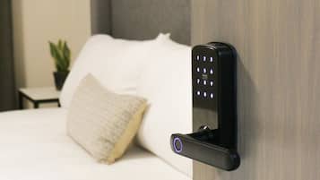 A modern room with a bed, a wall-mounted electronic device, and a small potted plant.