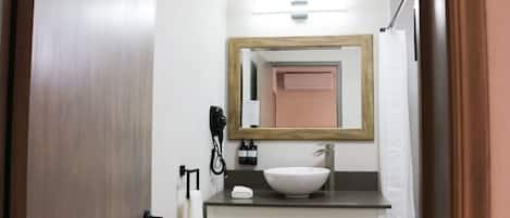 A bathroom with a wooden door, a white sink, a mirror, and a towel rack.