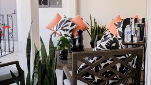 Een eethoek met een houten stoel, zwart-wit gestreepte kussens en een tafel met een waterfles en een thermoskan.