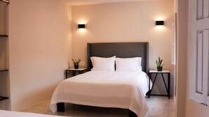 Een moderne hotelkamer met een groot bed, twee nachtkastjes met potplanten en wandlampen.