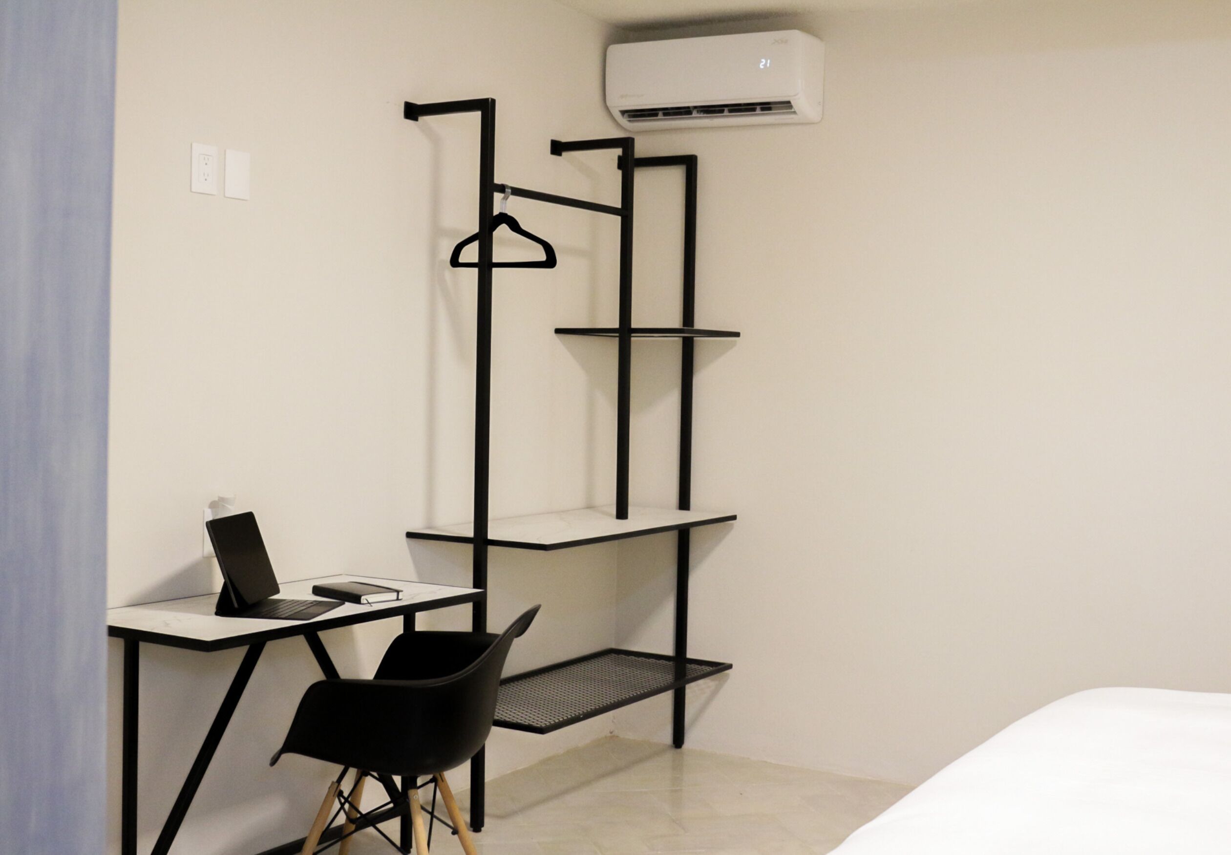 Habitación compacta con escritorio, silla y perchero.