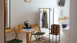 A room with a wooden table, two chairs, a small stool, a mirror, a coat rack, and a wall-mounted shelf. - Room 'Studio 3' with Private Terrace, Wi-Fi and Air Conditioning (Paros)
