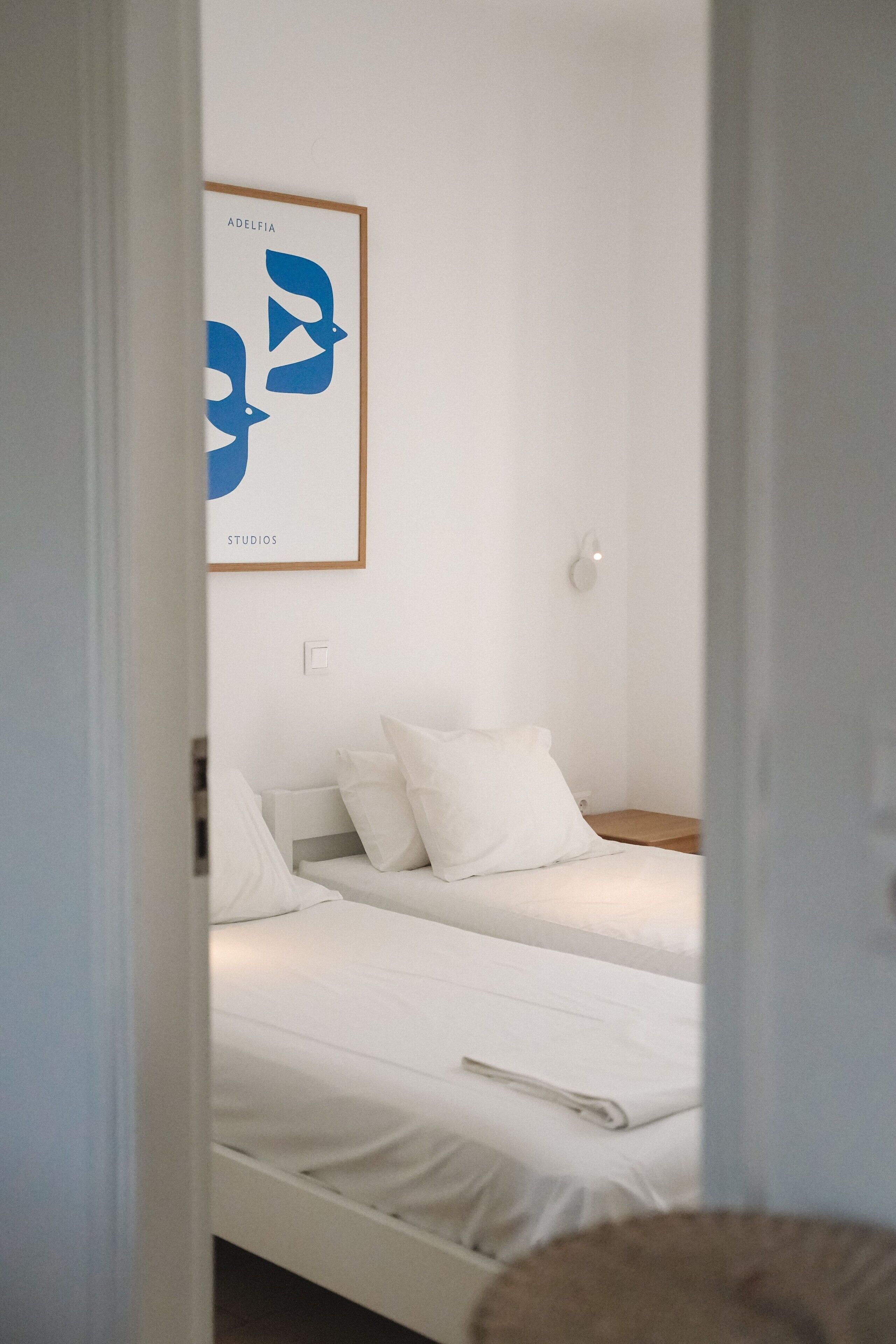 Una habitación con dos camas, una obra de arte enmarcada en la pared y un interruptor de luz.