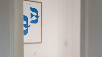 Una habitación con dos camas, una obra de arte enmarcada en la pared y un interruptor de luz.