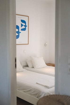 Une chambre avec deux lits, une œuvre d’art encadrée au mur et un interrupteur.