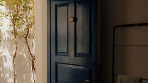 A room with a blue door, a metal rack with a towel, and a stone floor. - Studio Apartment '5' with Private Terrace, Wi-Fi and Air Conditioning (Paros)