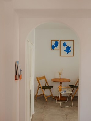 Un coin repas avec une table ronde, deux chaises et deux œuvres d’art encadrées accrochées au mur.