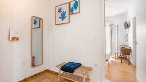 Une pièce comprenant un banc en bois, un miroir et deux œuvres d’art encadrées accrochées au mur.