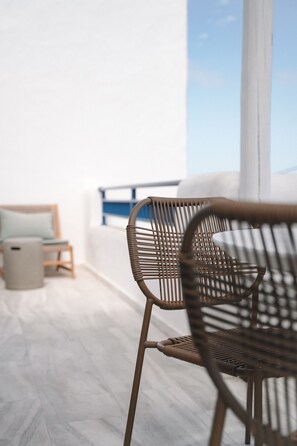 A modern interior with a wicker chair, a small table, and a view of the sky through a large window. - Apartment 'Studio 4' with Shared Garden, Wi-Fi and Air Conditioning (Paros)