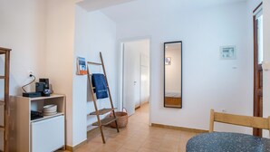 Une pièce comprenant une petite table, une chaise, une étagère avec des assiettes, une machine à café, une échelle et un miroir.