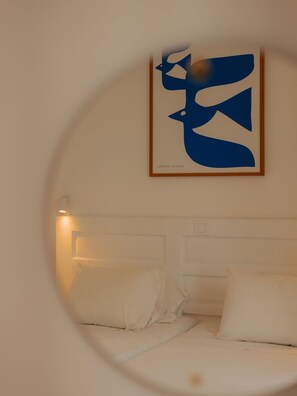 A bedroom with a bed, pillows, a wall-mounted artwork, and a bedside lamp. - Apartment 'Studio 4' with Shared Garden, Wi-Fi and Air Conditioning (Paros)