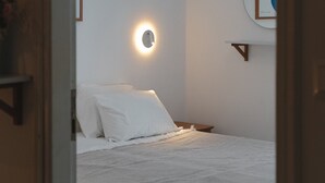 A bedroom with a bed, a wall-mounted air conditioner, a ceiling light, and a framed picture on the wall. - Studio Apartment '2' with Private Terrace, Wi-Fi and one Air Condition in the bedroom (Paros)