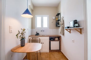 A compact kitchen with a dining table, a hanging light, a window, and a coffee machine. - Studio Apartment '15' with Mountain View, Wi-Fi and Air Conditioning (Paros)