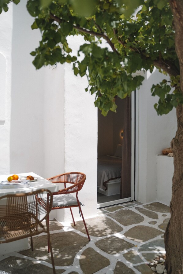 Eine Terrasse mit Tisch und Stühlen, einem Baum und einem Steinboden.