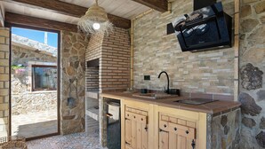 Cozinha de pedra e madeira com forno embutido, pia e luminária pendente.
