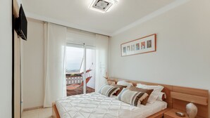 A bedroom with a bed, a nightstand, a TV, a sliding door, and a framed picture on the wall. - Vacation Apartment 'The Sunset' with Shared Pool, Wi-Fi and Air Conditioning (Costa Adeje)