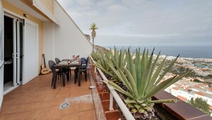 A balcony with a table, chairs, a guitar, and a large agave plant. - Vacation Apartment 'The Sunset' with Shared Pool, Wi-Fi and Air Conditioning (Costa Adeje)