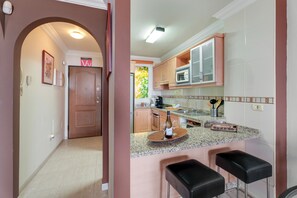 A modern kitchen with a bar area, wooden cabinets, and a countertop with a wine bottle and glasses.