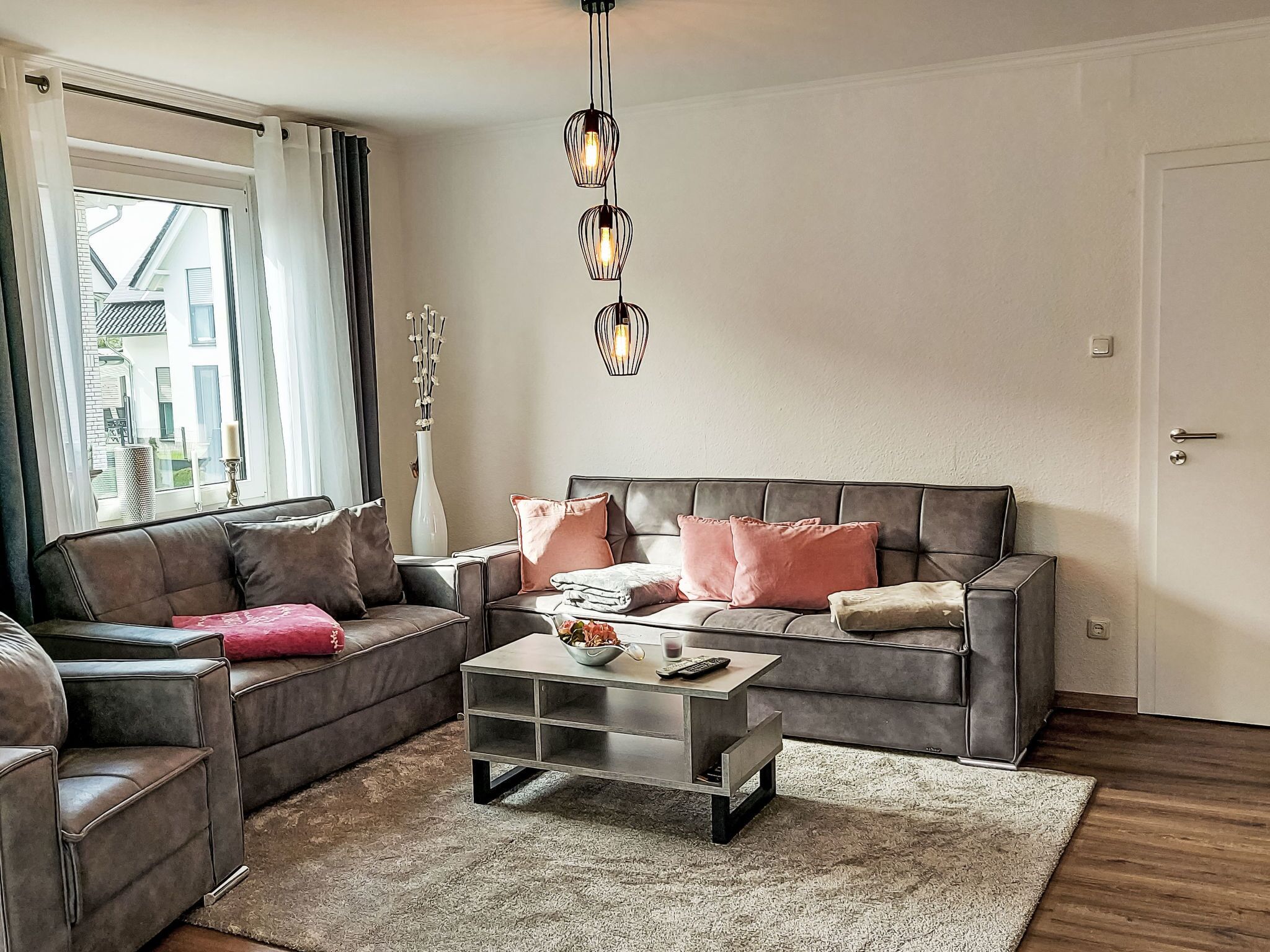 A living room with a grey sofa, a coffee table, and a chandelier.