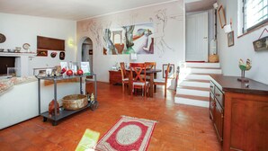 A spacious living area with a dining table, chairs, a kitchen area with a cart, and a staircase leading to another level. - Nice home in Tocco da Casauria (Tocco da Casauria)