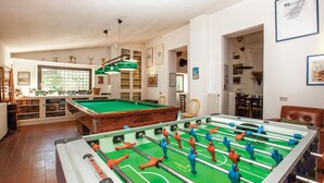 A room with a pool table, a foosball table, and a billiards table. There are shelves with books and trophies, and a window with blinds. - Nice home in Tocco da Casauria (Tocco da Casauria)