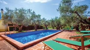 A rectangular swimming pool with a tiled border, surrounded by green lounge chairs and trees. - Nice home in Tocco da Casauria (Tocco da Casauria)