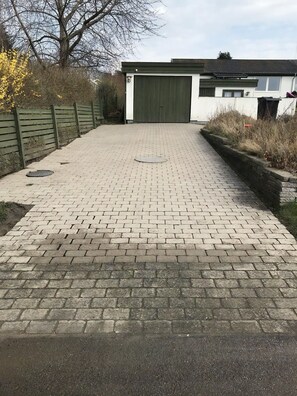 Ein gepflasterter Weg führt zu einem Gebäude mit einer grünen Garagentür.