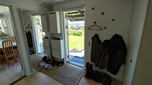 Une piĂšce comprenant un coin repas, un porte-manteau et une porte donnant sur un jardin.