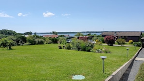 A residential area with a grassy lawn, a pathway, and a view of a lake. - Cozy summerhouse with spectacular views! (Ølsted)
