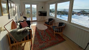 A living room with a sofa, chairs, a TV, and large windows with a view of a snowy landscape. - Cozy summerhouse with spectacular views! (Ølsted)