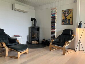 A room with two leather chairs, a fireplace, a bookshelf, and a painting on the wall. - Cozy summerhouse with spectacular views (Ølsted)