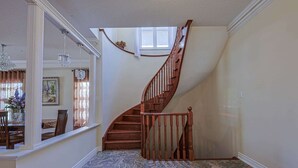 A staircase with wooden railings leading to an upper floor, a dining area with chairs and a table, and a patterned floor. - Harmony House: 7-BR Multi family & Group Oasis with Dual Living (Richmond Hill)
