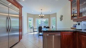 A kitchen with stainless steel appliances, wooden cabinets, and a view to the outside. - Harmony House: 7-BR Multi family & Group Oasis with Dual Living (Richmond Hill)