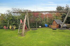 A playground with a swing set, tire swings, and a wooden climbing structure.