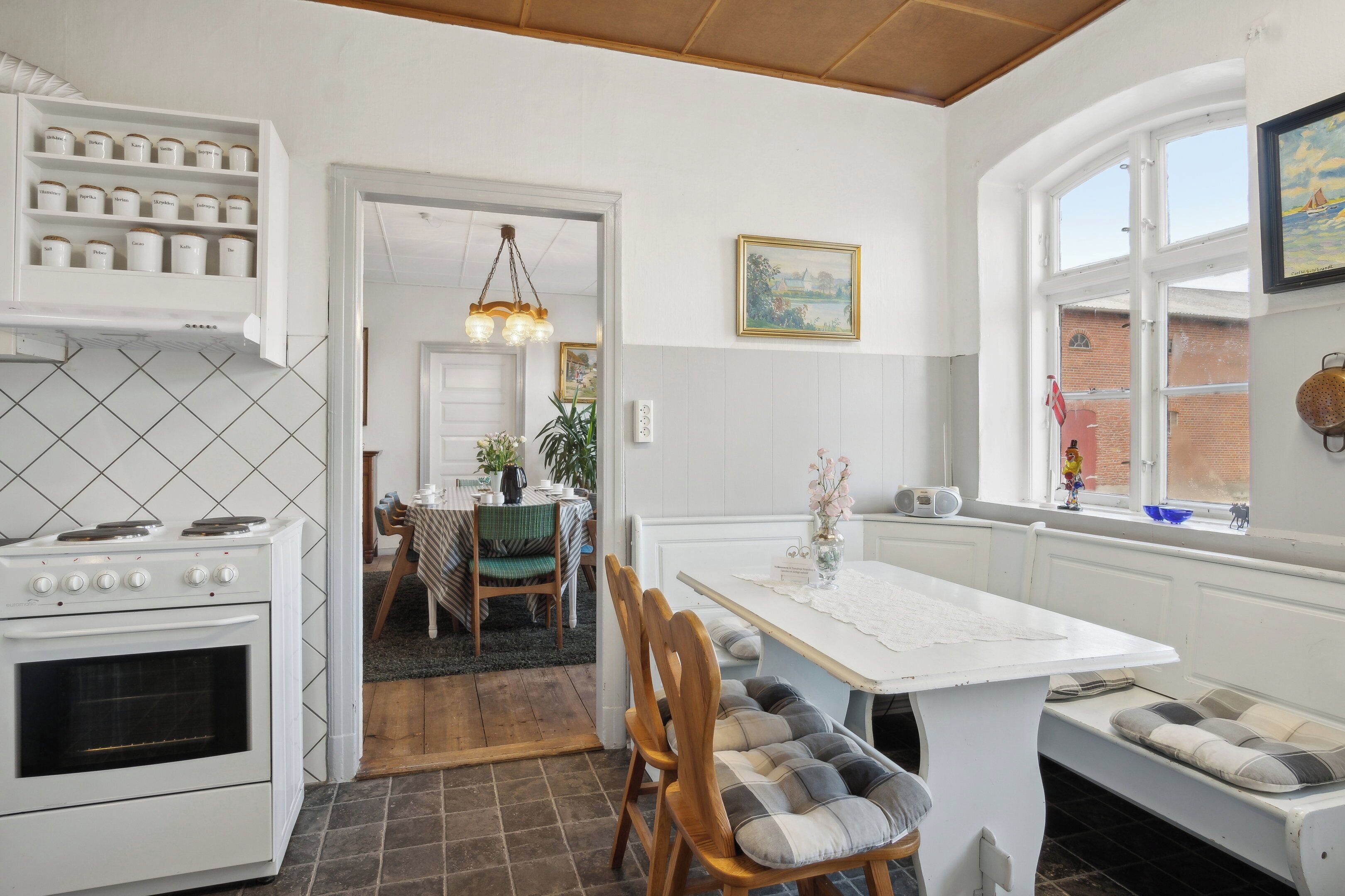 A kitchen with a stove, cabinets, and a dining area with a table and chairs.