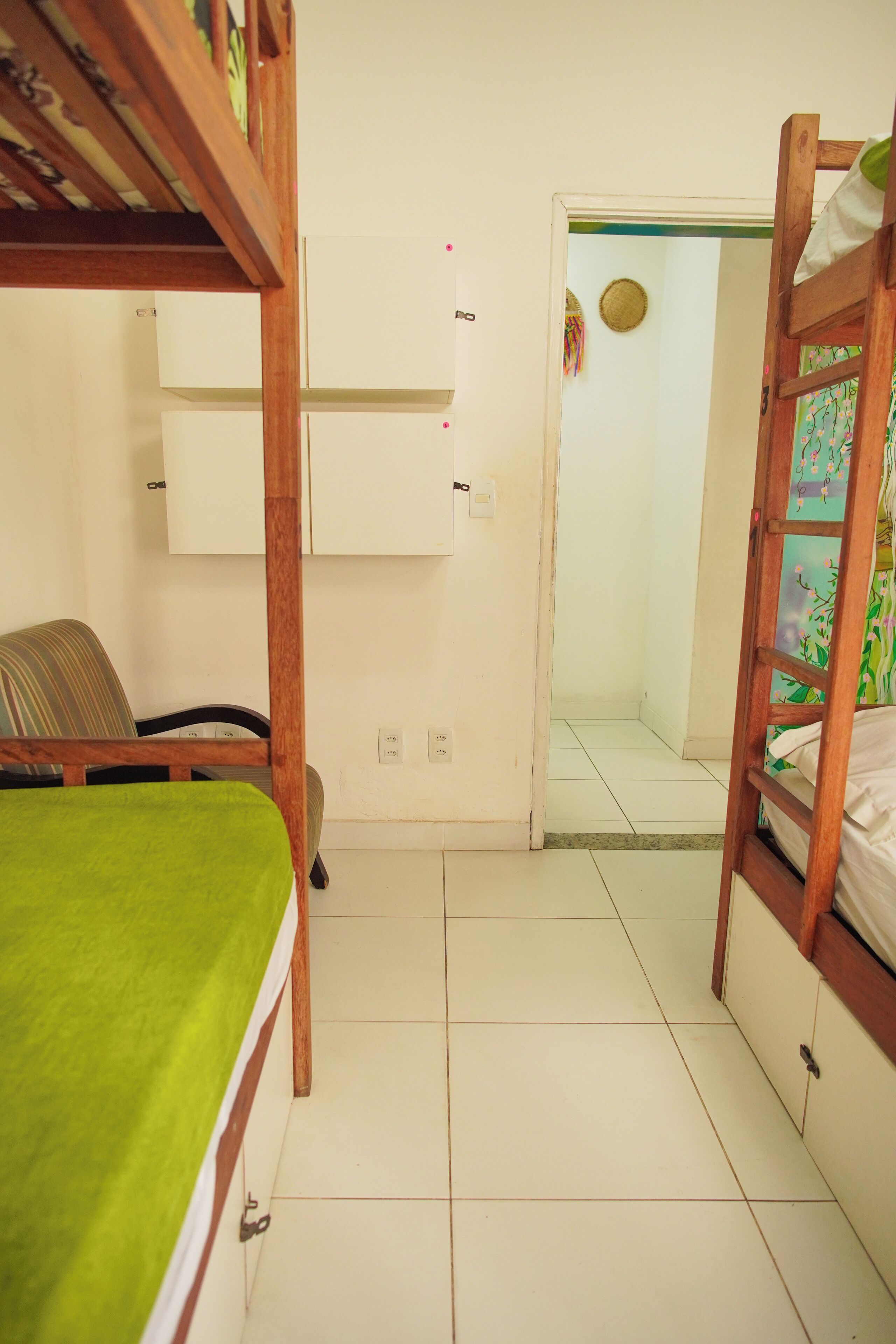 Quarto com beliches, uma escrivaninha e uma porta que dá para outro quarto.