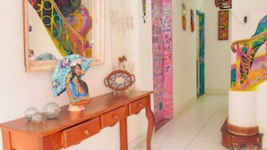A hallway with a wooden console table, a mirror, and a colorful staircase. - SOLCITY HOSTEL (Salvador)