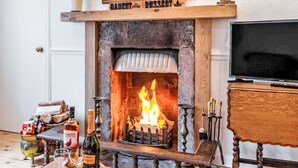 A cozy room with a fireplace, a television, and a table with a bottle of wine and glasses. - Vacation home Dancot by Interhome (Drumnadrochit)