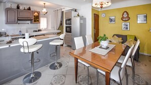 A modern kitchen with a central island, white bar stools, a dining table with chairs, and a yellow accent wall. - 1 bedroom cozy home in Moustiers-Sainte-Marie (Moustiers-Sainte-Marie)